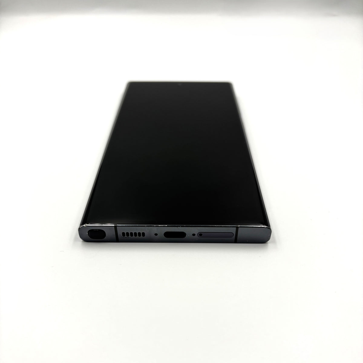 A black Samsung Galaxy S23 Ultra shown from the back, positioned horizontally on a plain white surface.