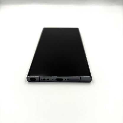 A black Samsung Galaxy S23 Ultra shown from the back, positioned horizontally on a plain white surface.