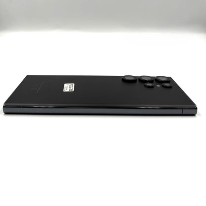 A black Samsung Galaxy S23 Ultra device shown from the back, positioned horizontally against a clean white studio background.