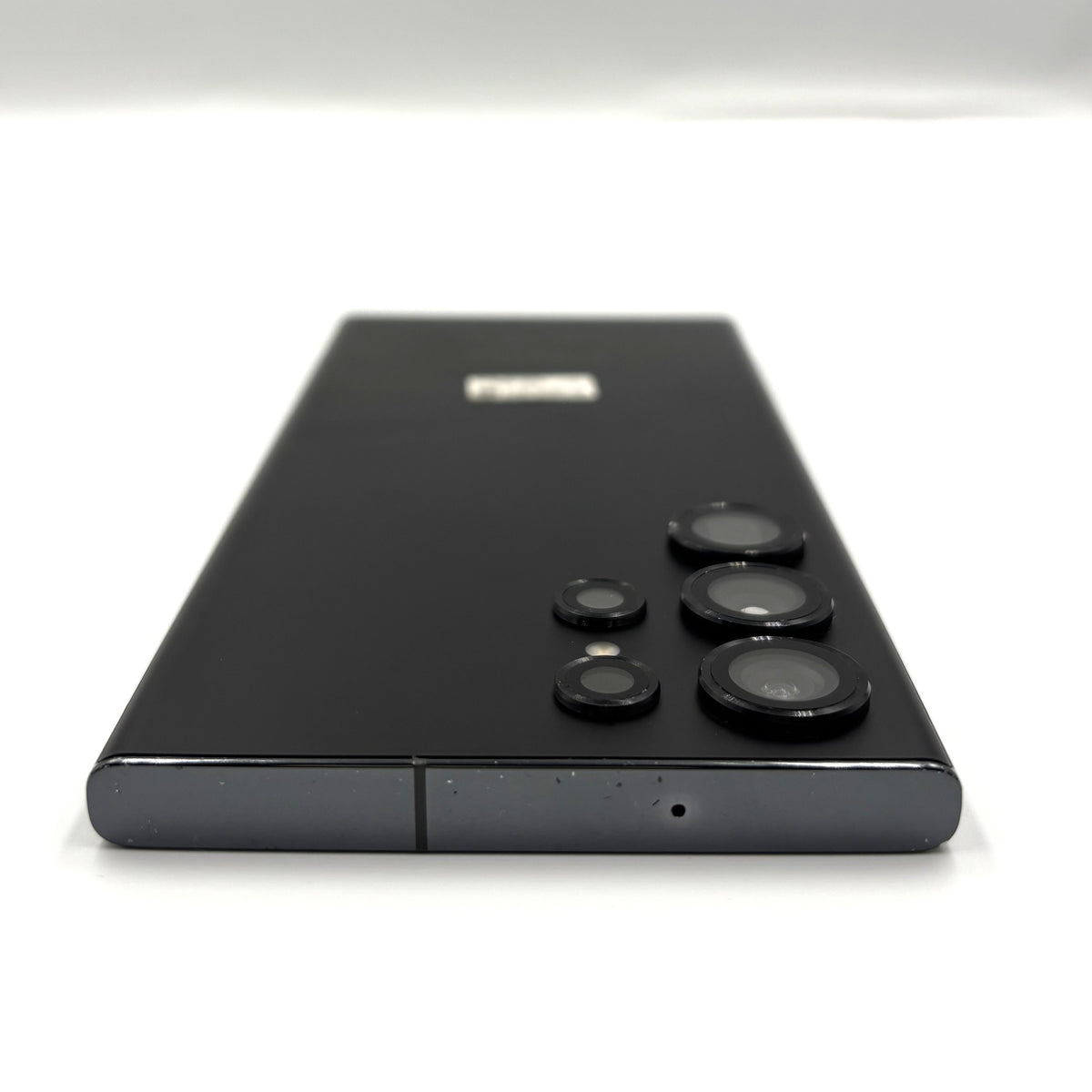 A black Samsung Galaxy s23 Ultra smartphone shown from the back, featuring its distinctive multi-camera array and a small silver logo near the top, set against a plain white background.
