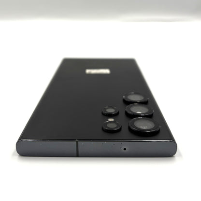 A black Samsung Galaxy s23 Ultra smartphone shown from the back, featuring its distinctive multi-camera array and a small silver logo near the top, set against a plain white background.