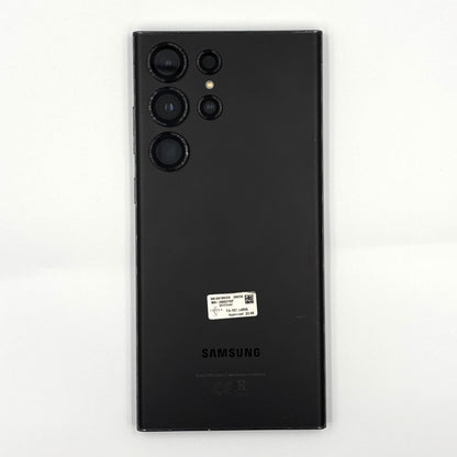 A black Samsung Galaxy S23 Ultra smartphone shown from the back, featuring its triple-camera system and a small white product sticker, set against a plain white background.