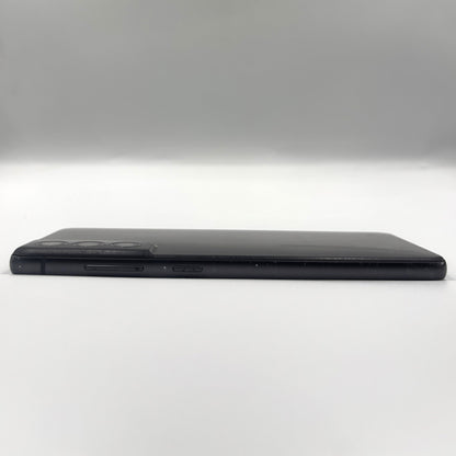 A black Samsung S21 Fe shown from the side, displaying its slim profile, camera cutout, and side buttons against a neutral gray studio background.