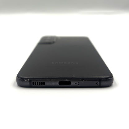The back of a black Samsung smartphone, showing the camera module, speaker grille, charging port, and side button, photographed on a white background.