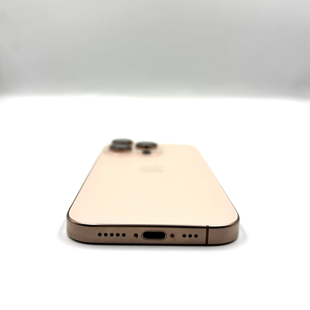 A Desert Titanium iPhone 16 Pro  smartphone shown from the back, positioned centrally against a clean white studio background.
