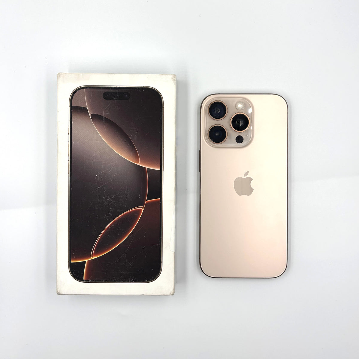 A Desert Titanium Apple iPhone 16 Pro shown next to its original white retail box on a clean white background.