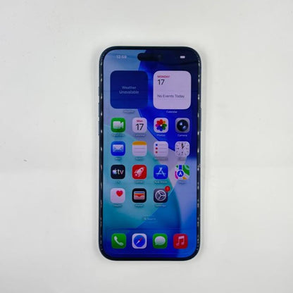 A iPhone 17 Pro Max with a lit screen displaying its home screen and widgets, photographed from above on a light off-white background.