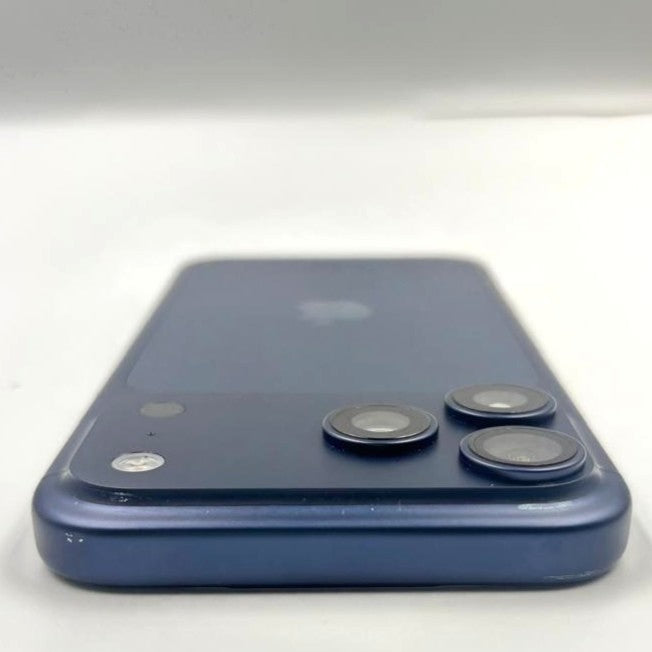 The back of a blue iPhone 17 Pro max, showing the rear camera array and a faint Apple logo in the center, photographed on a plain light background.